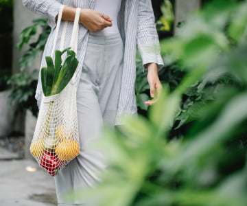 female carrying a bag of vegetables and fruits