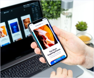 A computer and a person showing hands while holding a phone